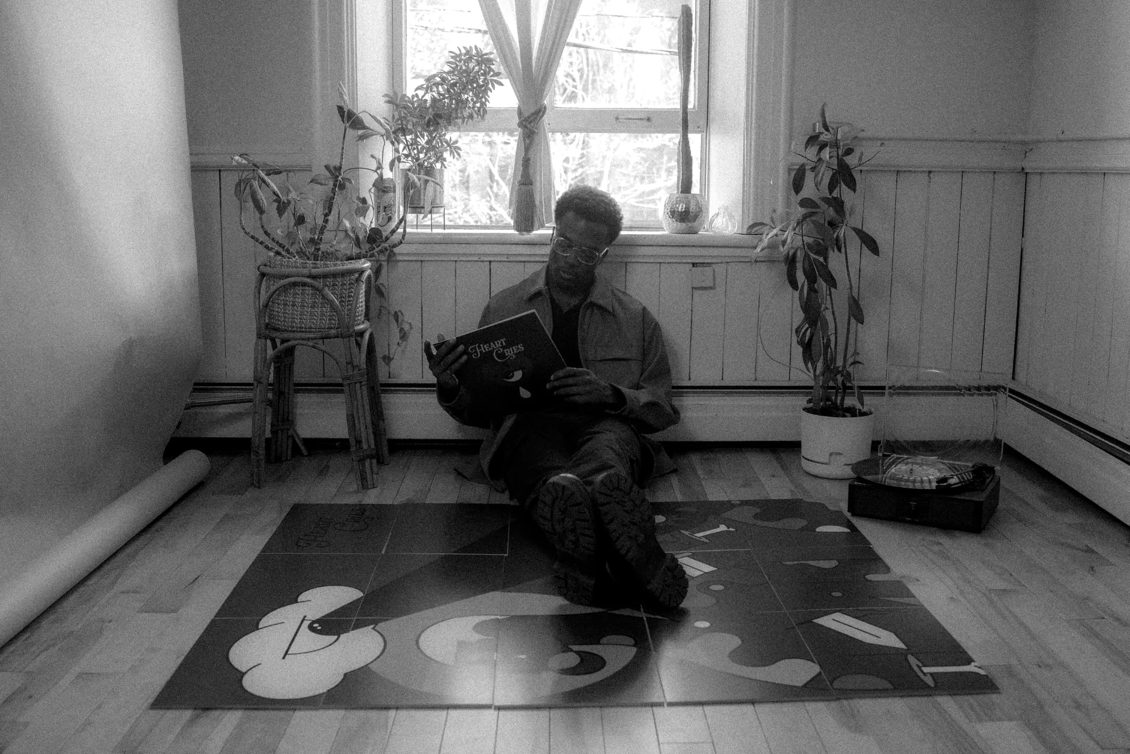 Niyi Adeogun seated in a studio with Heart Cries artwork